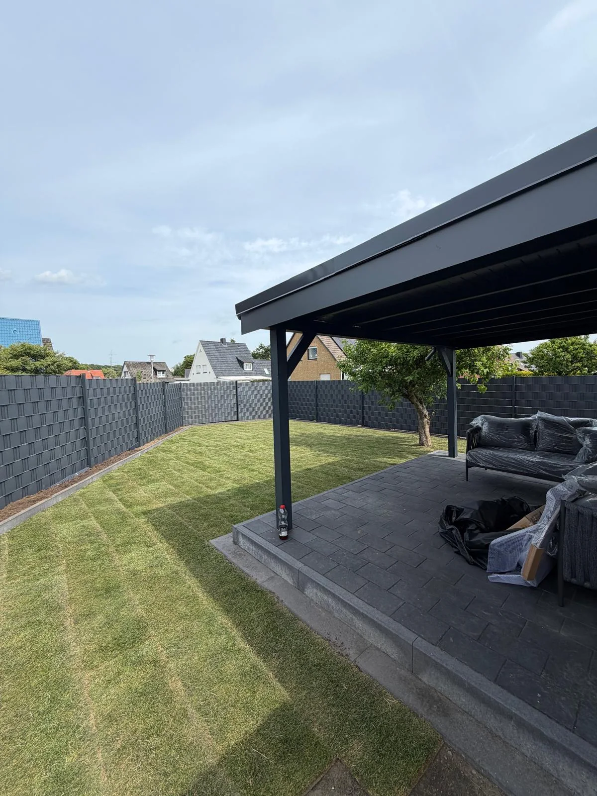 Rasenfläche neben Terrasse und Sichtschutzzaun